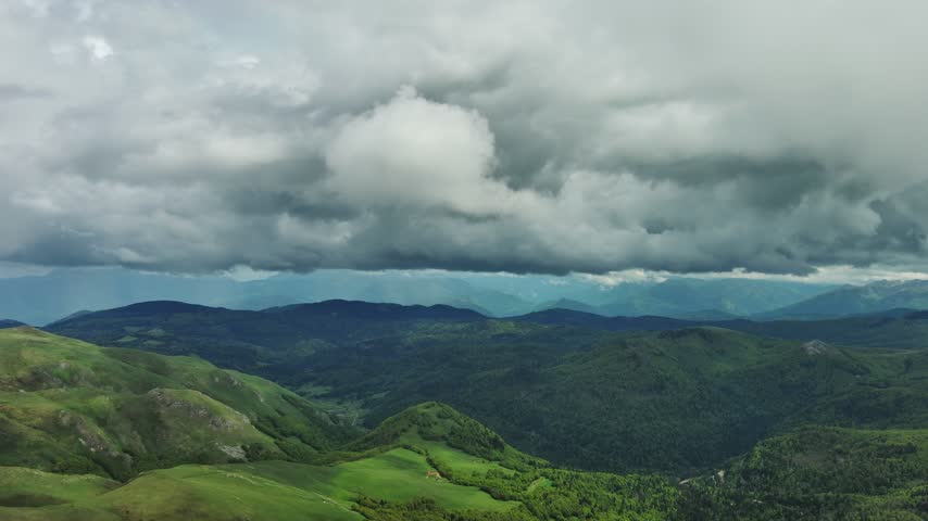 Aerial view of green mountains under a dramatic cloudy sky in Montenegro.
