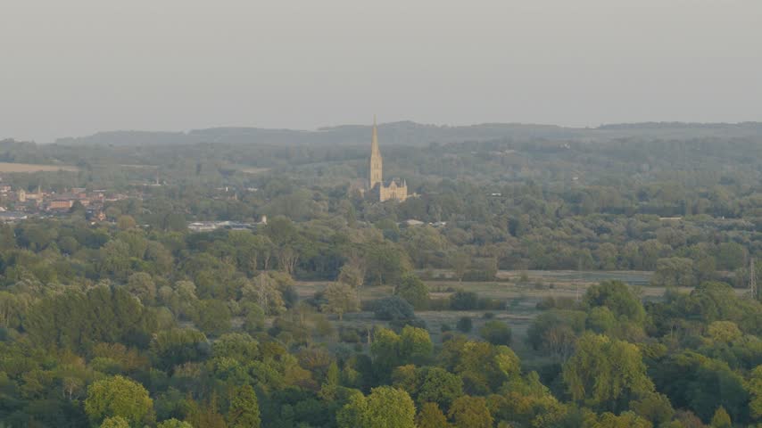 Telephoto view towards Salisbury Cathedral in Wiltshire England with its distinctive medieval spire rising above trees countryside and the surrounding landscape