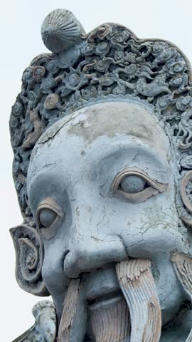 Slow tilt down along an ancient Chinese stone guardian statue at Wat Pho in Bangkok.