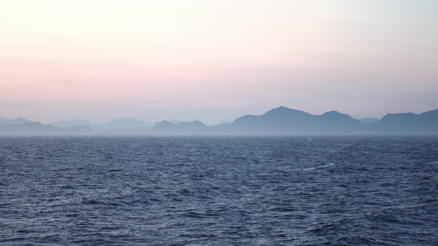 Hazy mountain layers over the sea at dusk in Alaska