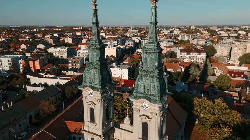 Aerial view of the historic Church of the Assumption of the Virgin Mary with its twin towers and clock faces, overlooking the urban rooftops of Pancevo, Vojvodina, Serbia.