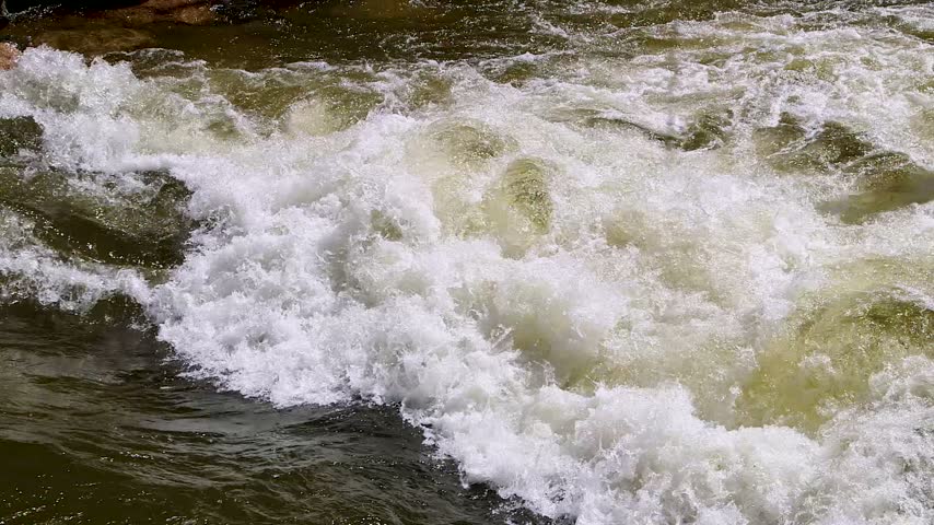 wide shot of rushing rapids on a river in the mountains