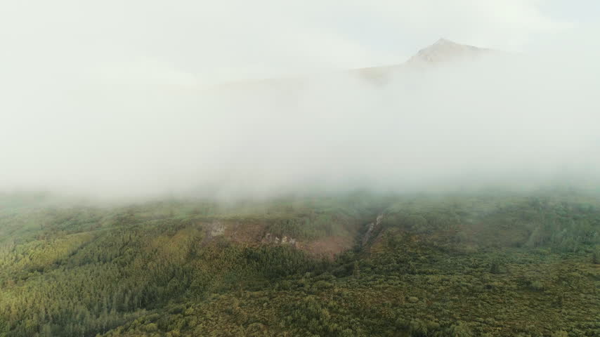 Fog bank rolling over a mountainside in Alaska aerial