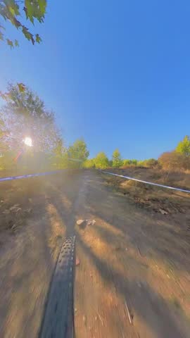 Sun flare shining on a blue sky while riding a mountain bike through gravel paths and single tracks front wheel point of view