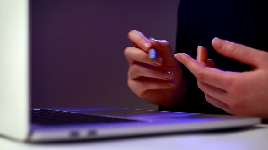 A person holds a pen and gestures while discussing social media marketing tools on a laptop screen. The time is during a training session in a modern office.