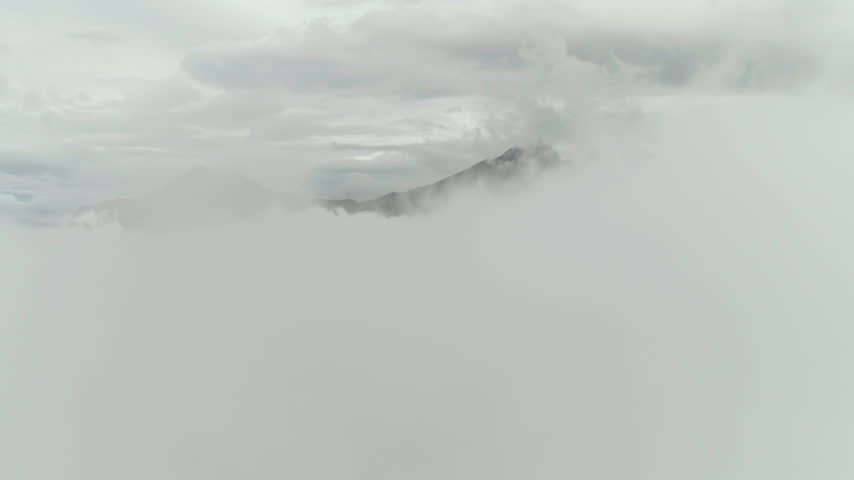 Mountain peaks rising above a sea of clouds in Alaska aerial