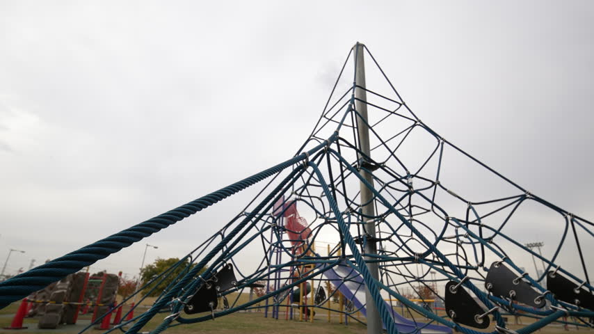 Wide shot of a rope climbing structure in a park.
