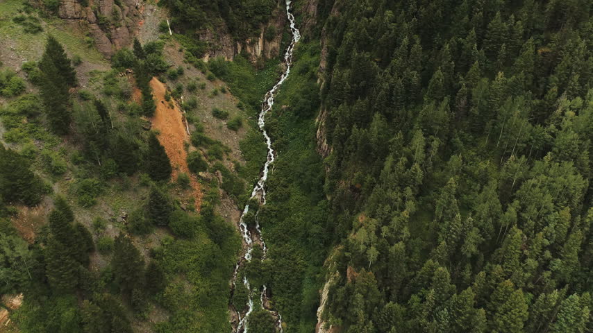 Cascading mountain stream in a forested gorge top down aerial