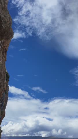Colorful eroded mountain ridges extend beneath a deep blue sky filled with large white clouds.