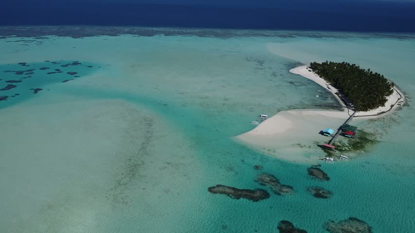 Wide aerial drone view of island in Balabac, Palawan, Philippines, revealing a remote tropical island surrounded by clear turquoise sea. Scenic island landscape showcasing the natural beauty of the Sulu Sea and the Philippines