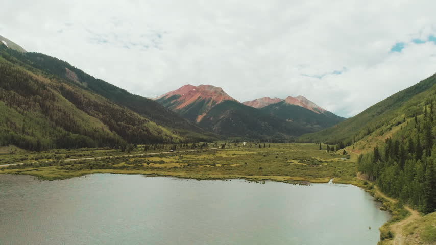 Alpine lake below red mountain peaks in Colorado aerial