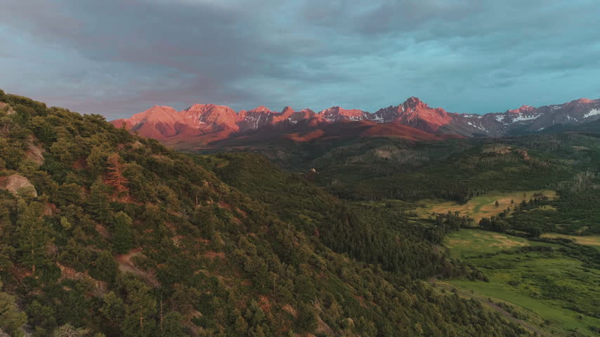 Alpenglow on a jagged mountain range at sunset in Colorado aerial