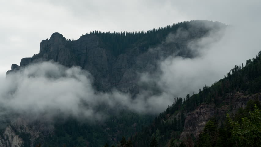 Low clouds drifting past a rocky cliff above Ouray Colorado timelapse