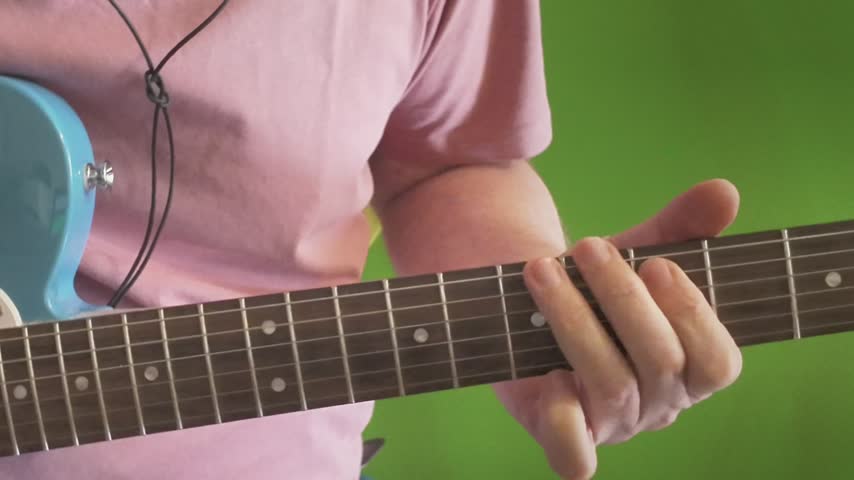 Guitar player performing on electric guitar in front of a green screen for chroma key compositing and video production.