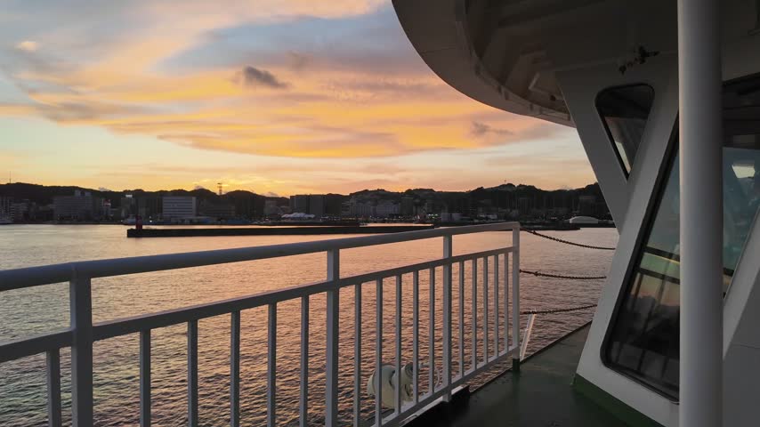 Sunset paints the sky over the harbor from a ferry deck.