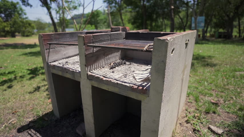 Concrete camping grills stand ready in a sunny recreational park for outdoor gatherings.