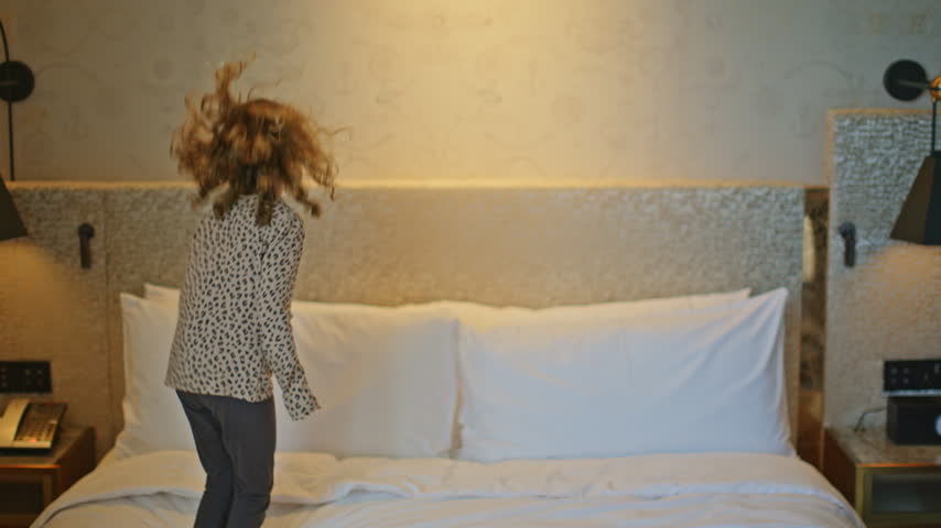 a small kid jumping on hotel bed 