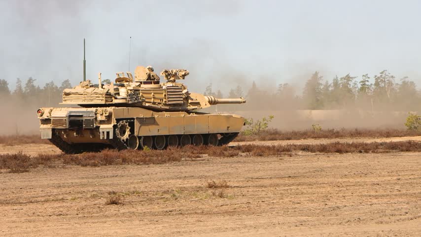 Heavy Military Battle Tank Moving Across Open Sandy Terrain During Tactical Training Operations In Desert.