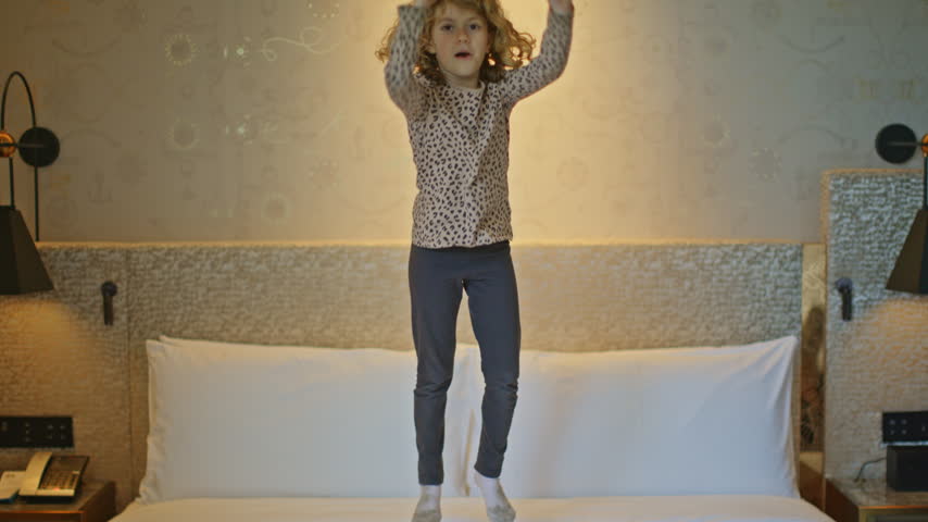 a small kid jumping on hotel bed 