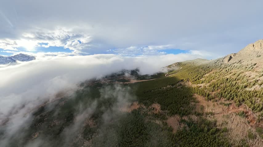 Aerial view of the rugged slopes of Twin Sisters Peak East partially obscured by thick rolling clouds in Larimer County, Colorado, United States.