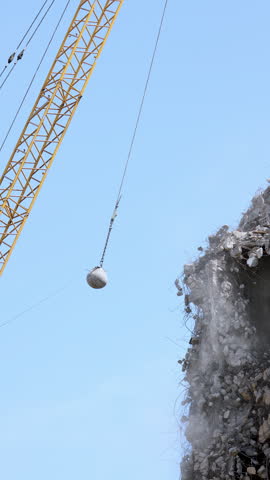 Heavy wrecking ball crane demolishing old building against blue sky in Magdeburg Germany. Building dismantling and construction waste disposal recycling service