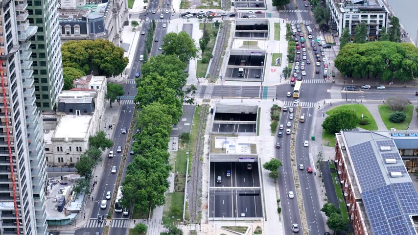Aerial view of highway tunnels and urban traffic surrounded by green trees and city buildings in Buenos Aires, Buenos Aires, Argentina.