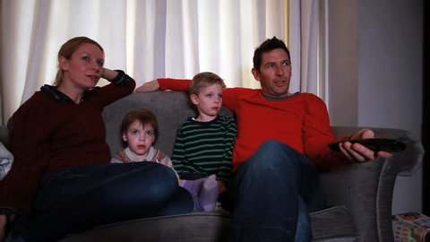 Family relaxing on sofa together watching tv