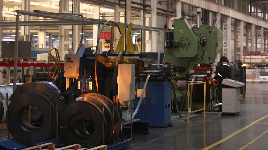Modern metalworking factory with an employee operating an automated sheet metal bending and punching machine, highlighting industrial production processes inside a large manufacturing facility