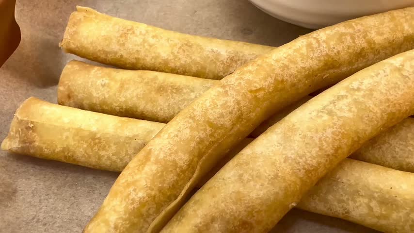 Close-Up of Golden Stick Harumaki Beside a White Dipping Bowl