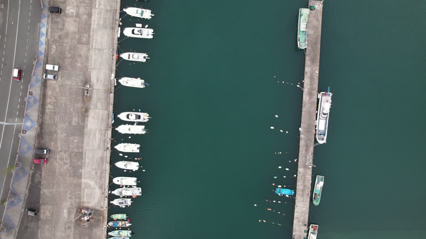 Top down aerial view along rows of moored boats and a parallel pier in Senzaki harbor Nagato Japan.