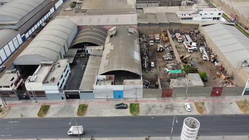 Traffic moving along avenida argentina past factories and junkyards in industrial lima, peru