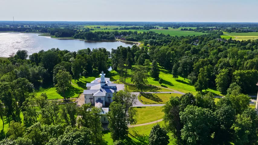 Aerial view of the historic Astravo dvaras manor house surrounded by lush green parkland and a large lake in Birzai, Panevezys County, Lithuania.