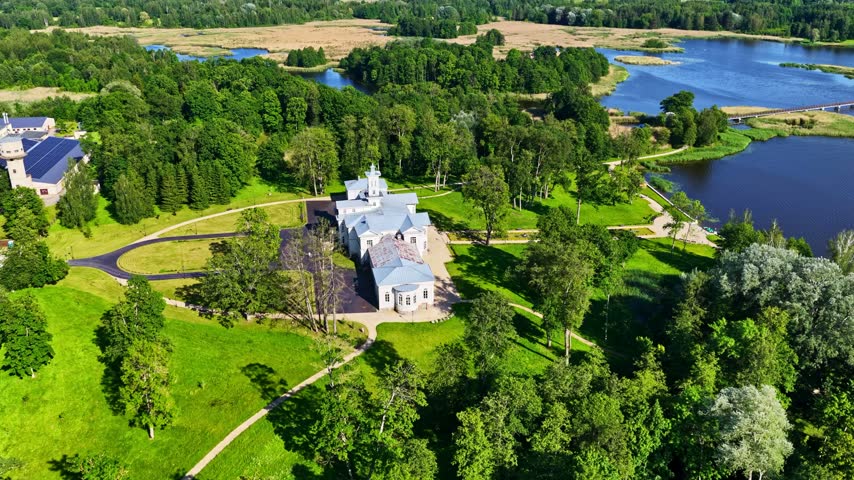 Aerial view of the historic Astravo dvaras manor house surrounded by lush green parkland and a large lake in Birzai, Panevezys County, Lithuania.
