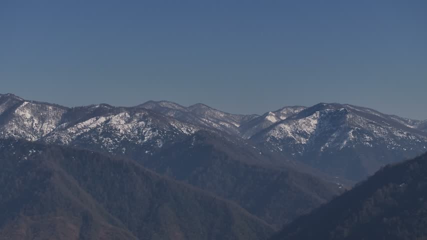 Aerial view of snow-capped mountains under a clear blue sky in Chakvi, Adjara, Georgia.