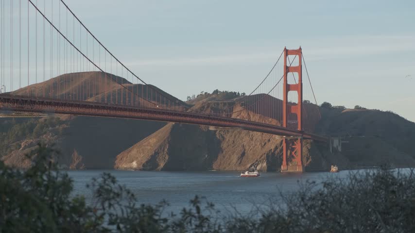 Boat passing under Golden Gate Bridge, San Francisco at sunset	