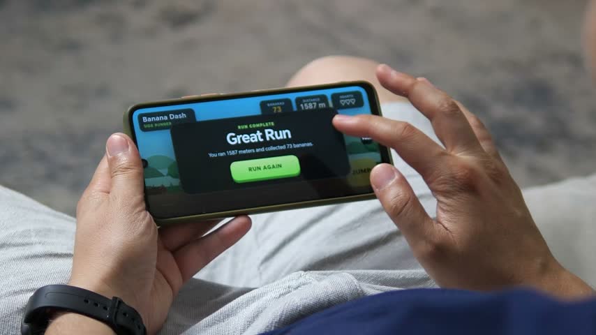 Person plays a colorful side runner game on a smartphone, jumping over obstacles and collecting items in a fast casual mobile gaming session.