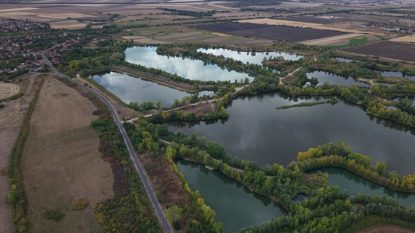 An aerial perspective showcases a cluster of interconnected lakes surrounded by lush green trees and autumnal foliage.