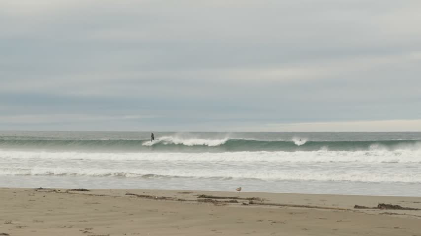 Surfer riding wave at overcast beach