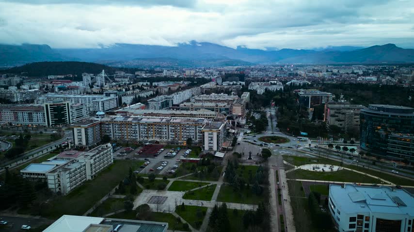 Panoramic aerial view of Podgorica cityscape with university park, boulevard, modern buildings and cloudy mountains in Montenegro