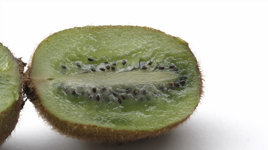 Detailed 4K macro cross section of kiwi fruit showing juicy green flesh and radiating black seeds.