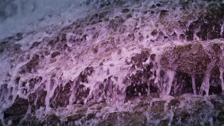 Rapid water crashes over jagged limestone steps at Rockway Falls in Ontario. Slow playback showcases churning pinkish white froth and suspended droplets bouncing off the wet stone shelf.