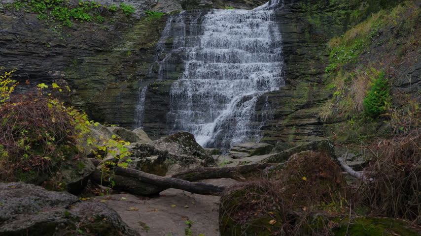 The main cascade drops down stratified rock cliffs into a scenic gorge at Rockway Falls, Ontario. Slow playback captures delicate water spray and misty droplets floating near the base.