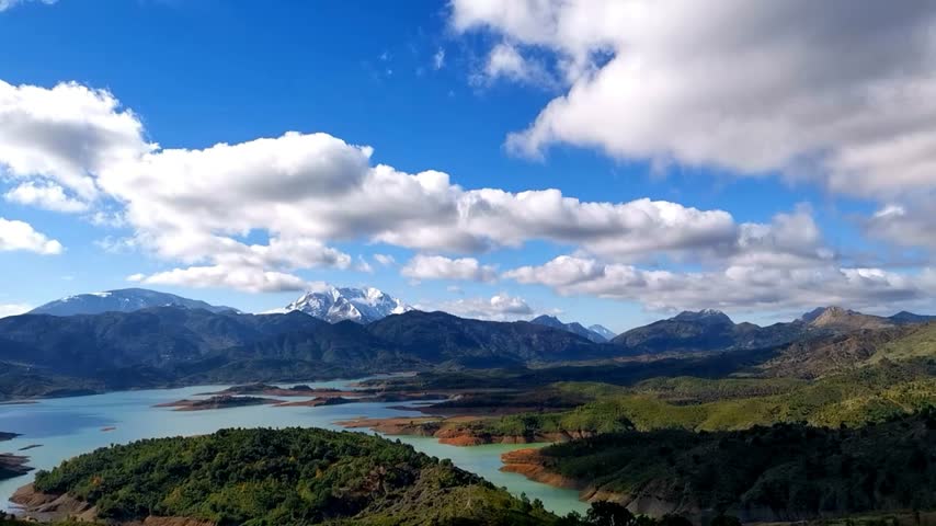 Time-laps of Beautiful landscape of lake of blue sky, clouds and mountains on surface of lake, Panoramic view of lake and snow-covered mountain and Forest trees in Jijel Algeria Africa.