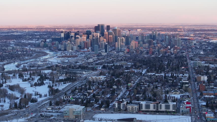 Aerial view of the downtown Calgary skyline and surrounding neighborhoods at sunset during winter in Calgary, Alberta, Canada.
