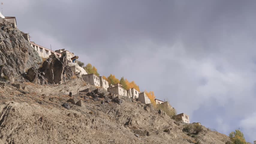 Monastery perched upon mountain top with golden yellow autumnal trees, time lapse shadow and light, copy space.
