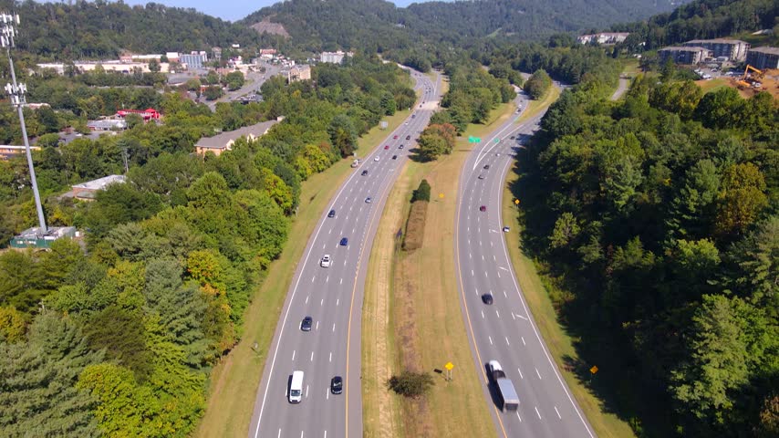 The camera tilts downward toward cars on a divided Asheville highway.