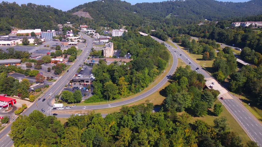 A curved ramp connects roadside development with a divided Asheville highway.
