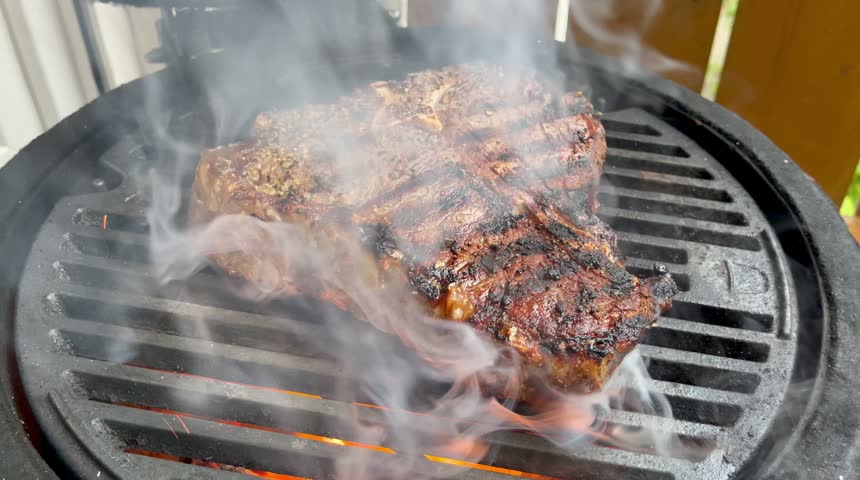 T-Bone Steak Sizzling on a Hot Barbecue Grill with Flames and Rising Smoke