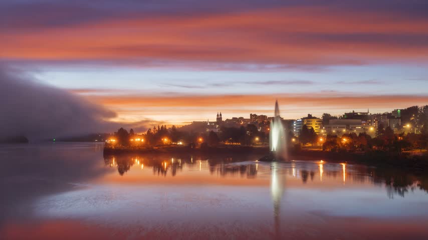 Chicoutimi, Quebec, Canada downtown skyline time lapse on the Saguenay River during a fiery sunrise.