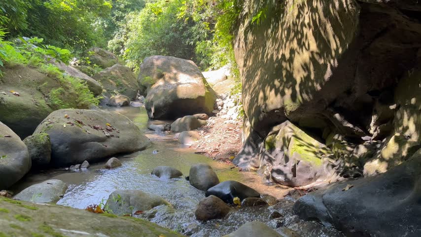 First-person perspective or steady shot of a rough and rugged pathway covered with wet stones in a tropical jungle. Shonaichori Trail, Mirshorai, Chittagong 